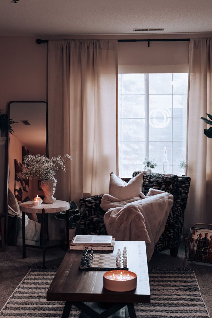 A stylish and cozy living room interior with warm lighting, featuring a wicker armchair and decorative elements.