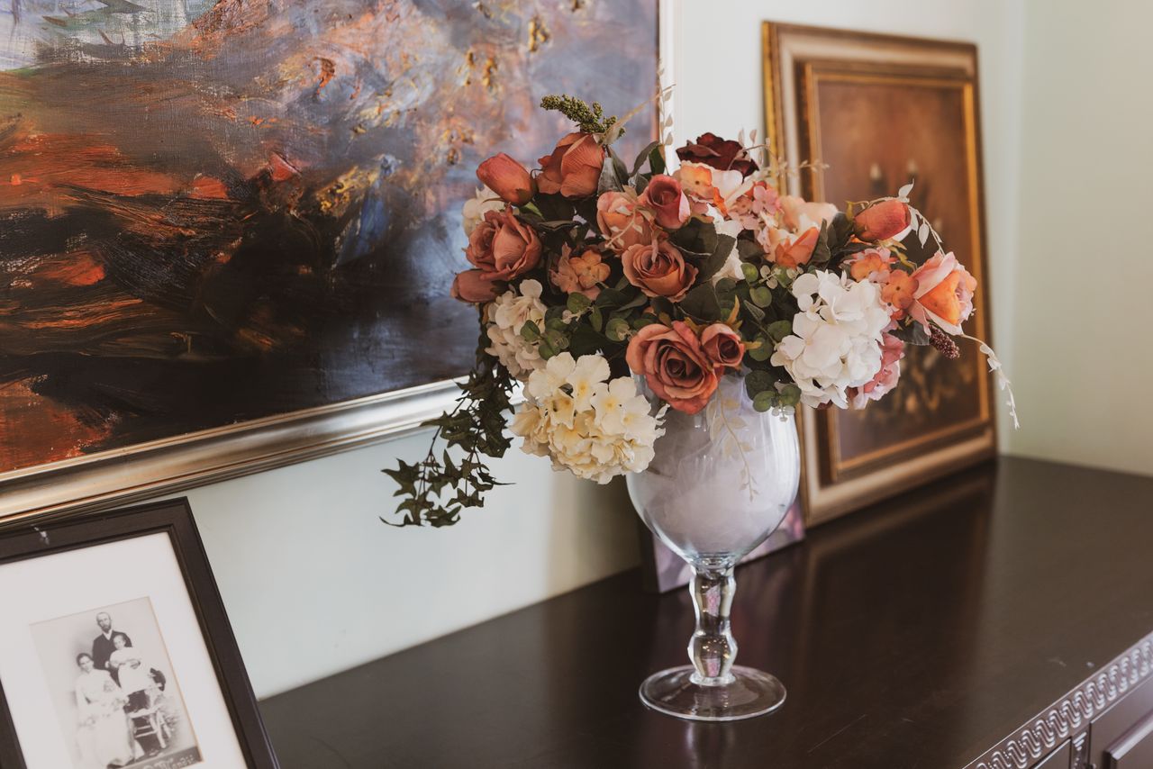 Beautiful floral arrangement in a vase against a backdrop of artistic paintings, perfect for sophisticated decor.