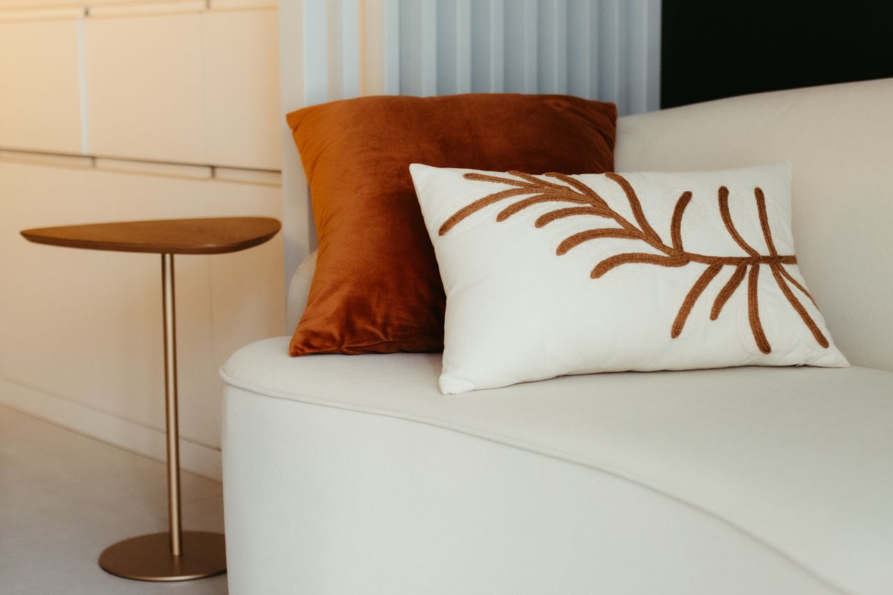 services-01 Elegant modern living room with stylish pillows on a cozy sofa beside a minimalist table.