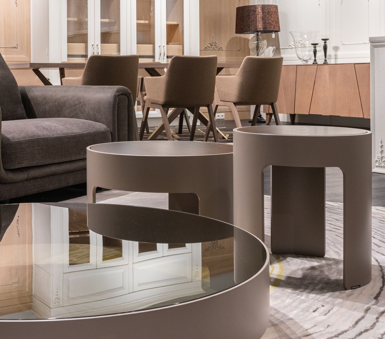 services-01 Small round tables placed near sofa and and sat of brown chairs at wooden cupboard with lamp and candlestick in modern apartment