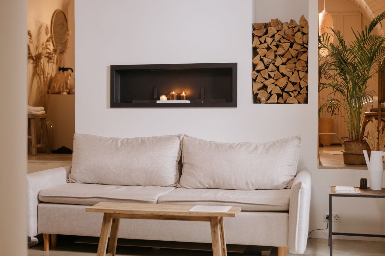 services-img A serene minimalist living room featuring a clean lined sofa, wooden accents, and ambient candles.
